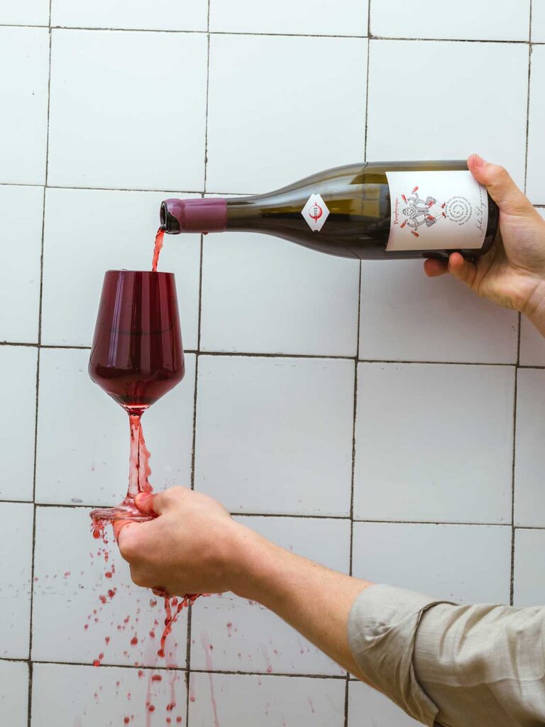 Ein Weinglas wird mit Rotwein überfüllt und läuft über